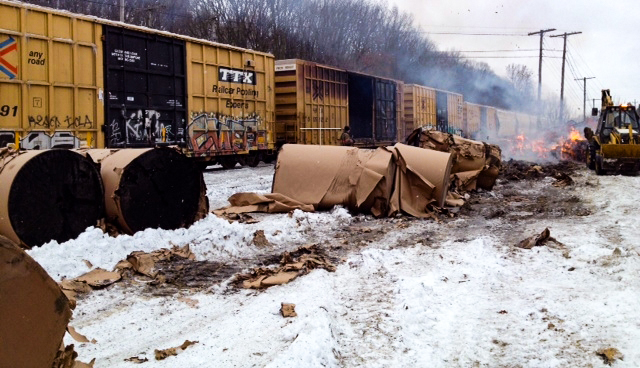 Image shows fire damaged medium paper rolls in snow after a train derailment